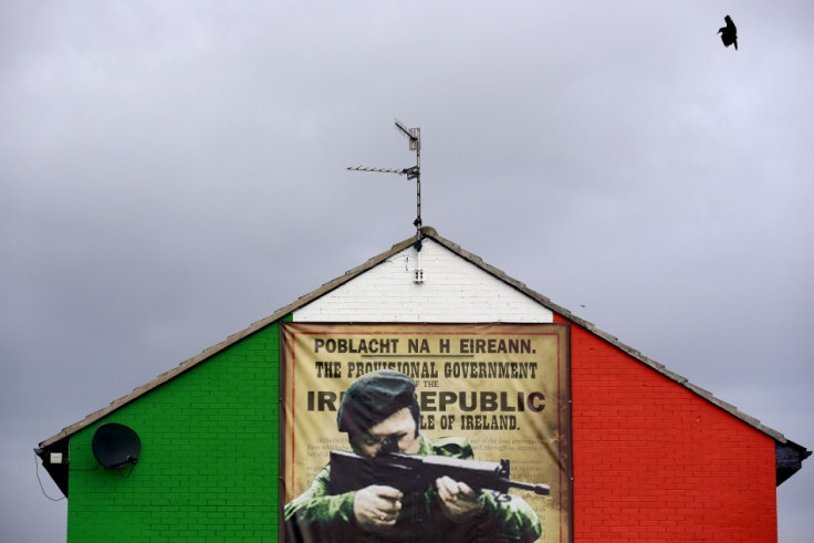 A crow flies past a mural in the Ardoyne area of North Belfast displaying an image of a I.R.A. gunman November 5, 2013