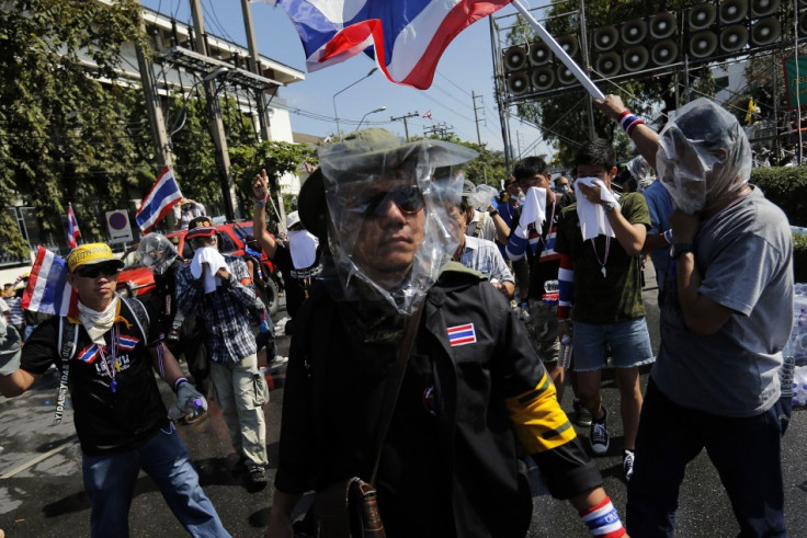 Masked anti-government protesters get ready to attack a barricade during clashes with police near the Government house in Bangkok