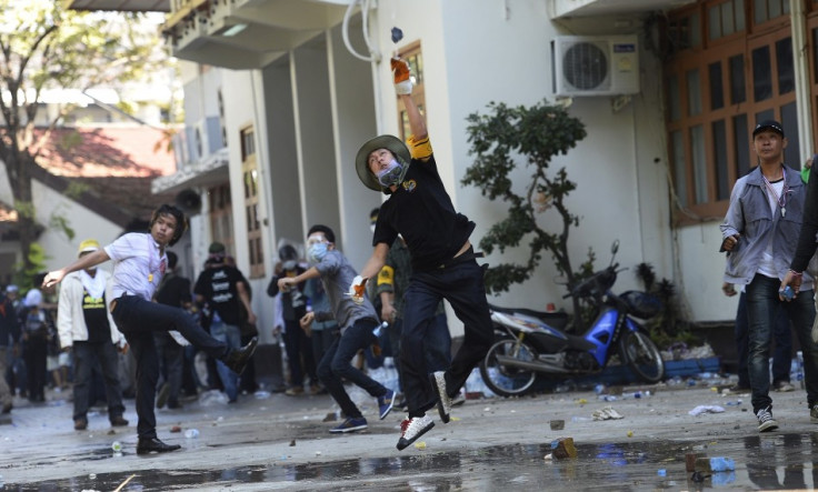 Anti-government protesters throw rocks at Thai Riot police as they attack Government House in Bangkok