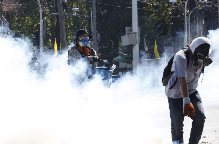 Anti-government protesters try to retrieve a teargas canister during clashes with police near the Government House in Bangkok