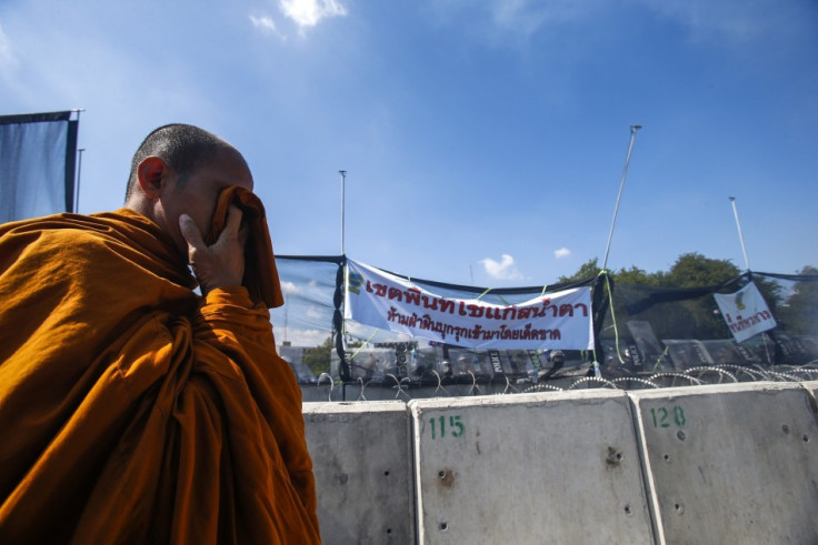 A Buddhist monk covers his face with wet handkerchief during clashes with police near government house in Bangkok
