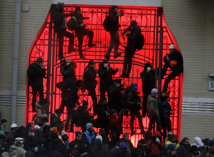 People climb up onto a gate near the presidential administration building during a rally held by supporters of EU integration in Kiev