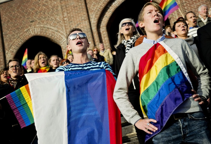 People sing the Russian national anthem while raising rainbow flags and a Russian flag (C) in solidarity with the lesbian, gay, bisexual and transgender (LGBT) community of Russia