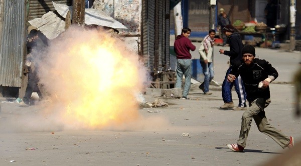 A Kashmir protester flees as a tear gas shell fired by Indian troops explodes nearly during a 2010 demonstration [].