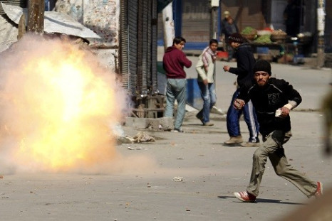 A Kashmir protester flees as a tear gas shell fired by Indian troops explodes nearly during a 2010 demonstration [].