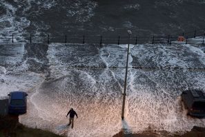 A man stands in water washed onto the promenade of the north bay in Scarborough (Reuters)