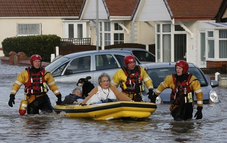 Emergency rescue service workers evacuate residents in an inflatable boat in flood water in a residential street in Rhyl (Reuters)