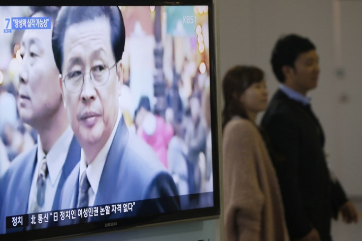 A couple walks past a television showing a report on Jang Song Thaek, North Korean leaders' uncle, at a railway station in Seoul