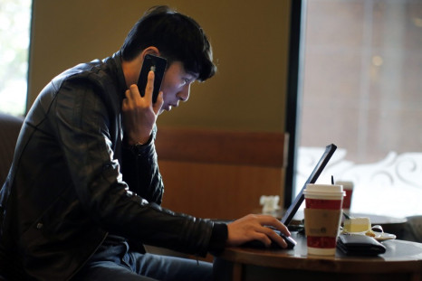 A man talks on the phone as he surfs the internet on his laptop at a local coffee shop in downtown Shanghai November 28, 2013. China's campaign against online rumours, which critics say is crushing free speech, has been highly successful in "cleaning