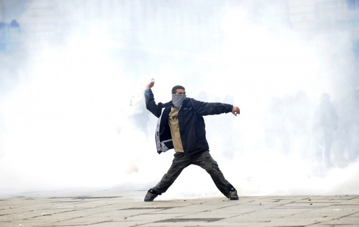 A protester throws a tear gas canister during a protest in downtown Turin