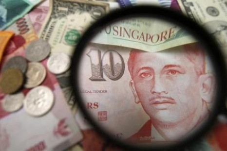 Singapore currency notes are seen through a magnifying glass among other currencies in this photo illustration taken in Singapore April 12, 2013.