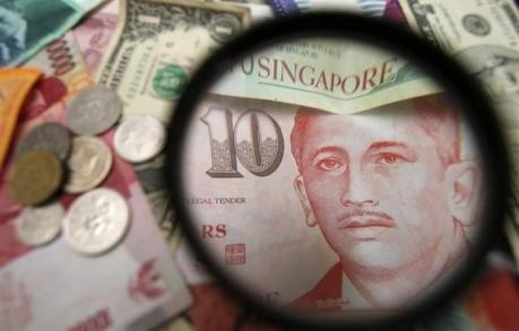 Singapore currency notes are seen through a magnifying glass among other currencies in this photo illustration taken in Singapore April 12, 2013.