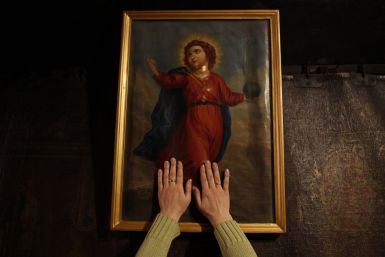 A worshipper places her hands on a painting of Jesus in the Grotto, where Christians believe Virgin Mary gave birth to Jesus, during her visit to the Church of the Nativity in the West Bank town of Bethlehem