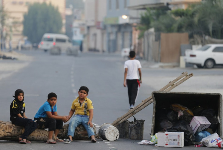 Children sit on a roadblock set up by protesters to prevent riot police from entering the village of Shakhoora, west of Manama,