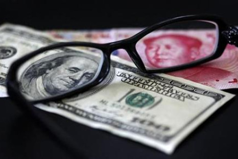 A U.S. dollar note and a Chinese yuan banknote are seen through a pair of spectacles in this picture illustration taken in Taipei