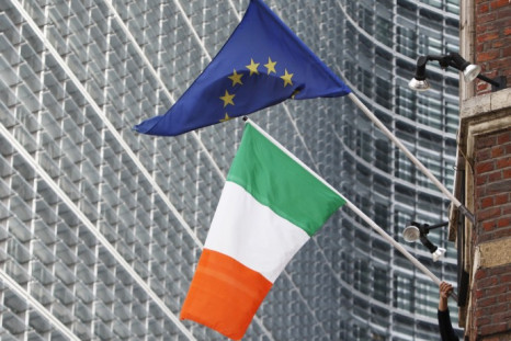 A man adjusts an Irish flag as it flies next to a European Union
