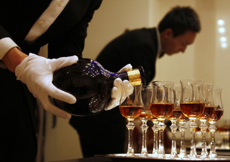 A waiter is reflected in a mirror as he pours Scotch whisky from luxury brand
