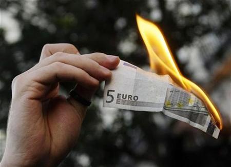A demonstrator burns a five euro note during a protest against capitalism in Madrid