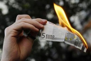 A demonstrator burns a five euro note during a protest against capitalism in Madrid