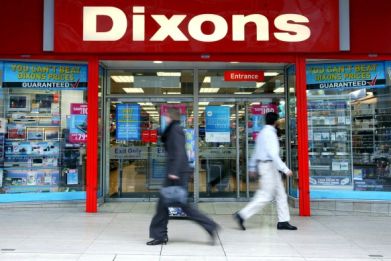 Pedestrians walk past a Dixons electrical retail shop in London