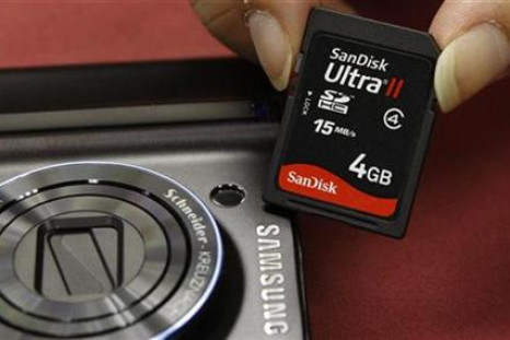 A shopper poses with a SanDisk memory card beside a Samsung camera in Hong Kong