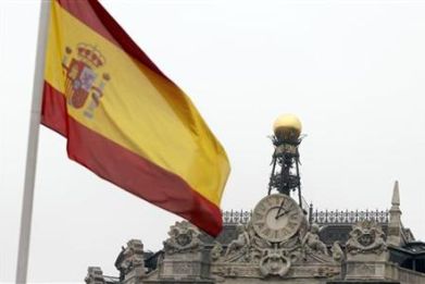 A Spanish flag flutters near the dome of the Bank of Spain in central Madrid