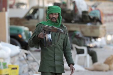 A Libyan soldier loyal to leader Muammar Gaddafi stands in a street strewn with rubble in the city of Misrata, 200 km (124 miles) east of the capital Tripoli March 28,2011.