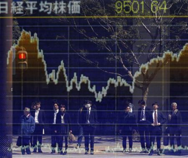 People are reflected on a stock quotation board displaying the Nikkei share average outside a brokerage in Tokyo