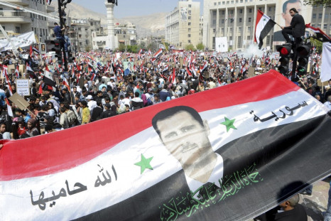 Syrians display a giant national flag with a picture of Syria's President Assad during a pro-government rally at the central bank square in Damascus