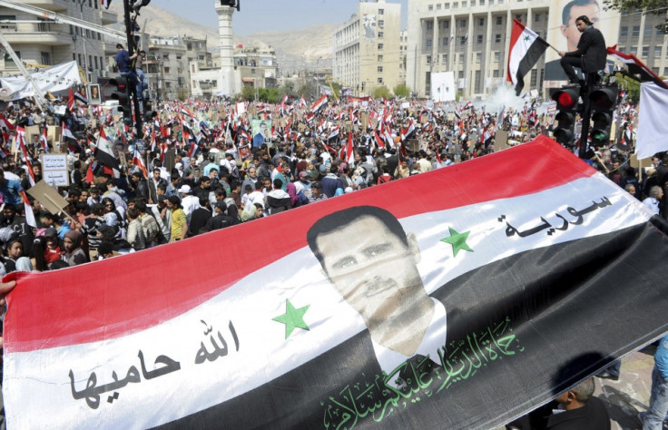 Syrians display a giant national flag with a picture of Syria's President Assad during a pro-government rally at the central bank square in Damascus