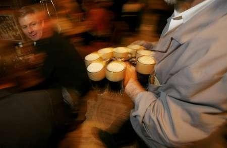 A patron watches as a barman brings a round of beers