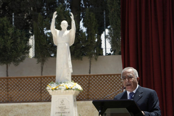 Palestinian PM Fayyad speaks in front of a statue of Pope John Paul II during a ceremony in Bethlehem