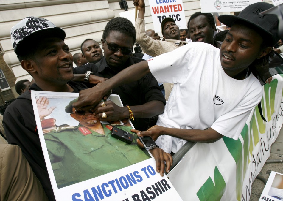 A protester defaces a picture of Sudanese President Bachir outside the Sudanese Embassy in London
