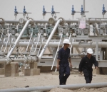 Workers walk at Rumaila oilfield in Basra, 420 km (260 miles) southeast of Baghdad